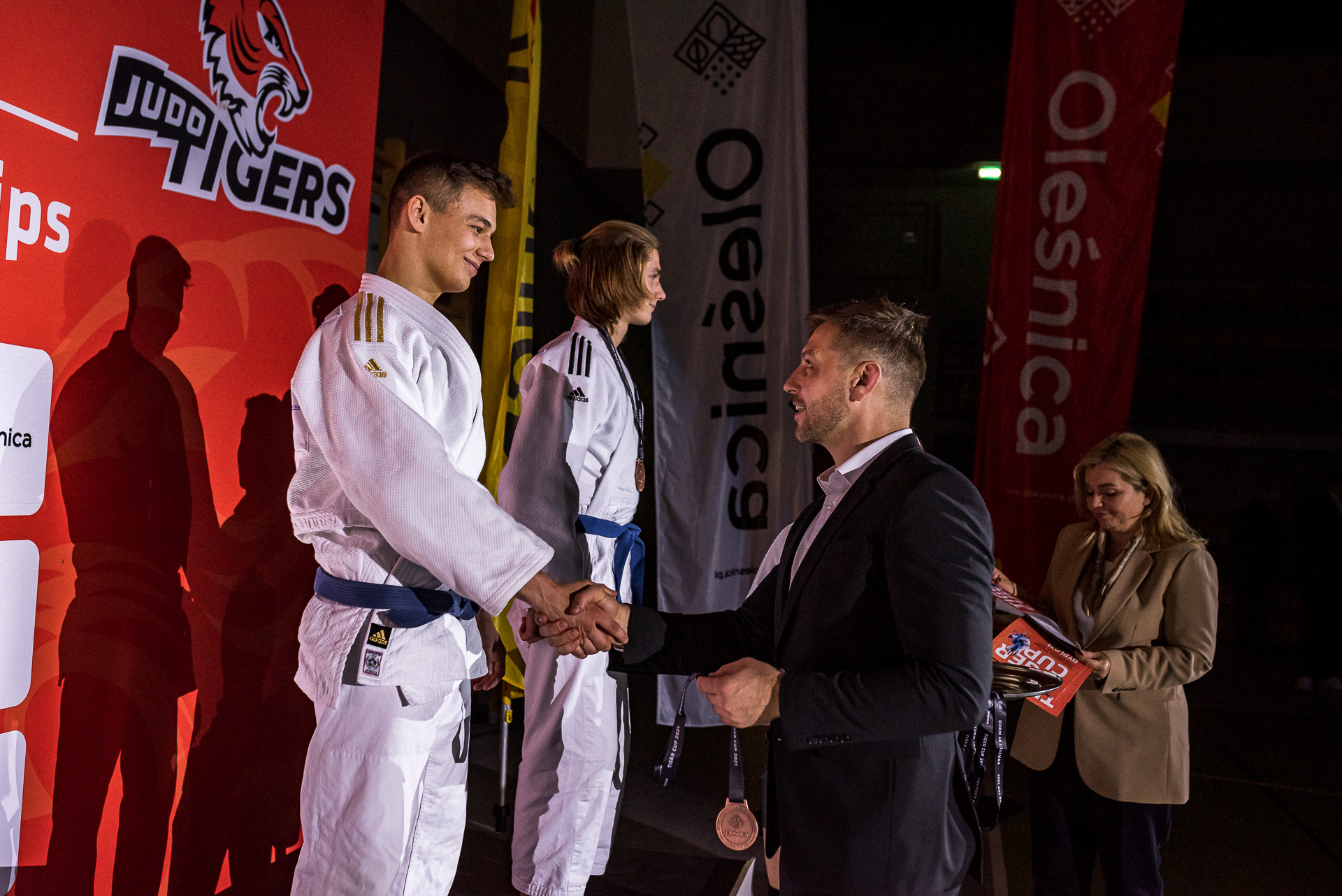 Tiger Cup 2021. Michał Zamęcki (prezes KS Judo Tigers) dekoruje swojego wychowanka na podium kategorii do 60 kg (Mikołaj Szopa).