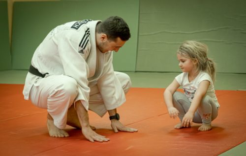 Trener Michał Cepuch tłumaczący ćwiczenie dziewczynce w wieku przedszkolnym (Judo Tigers)